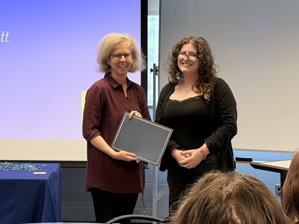 Close-up of a faculty member and a student smiling while holding a French program award certificate.